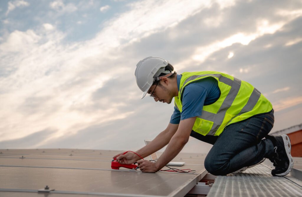 Roofer in a hard hat kneeling to repair a roof